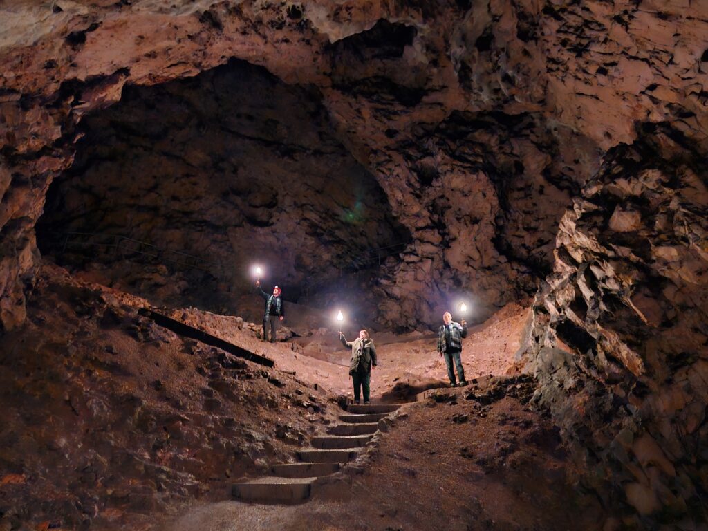 Drei Menschen in der Hohle Fels Höhle mit Fackeln in der Hand